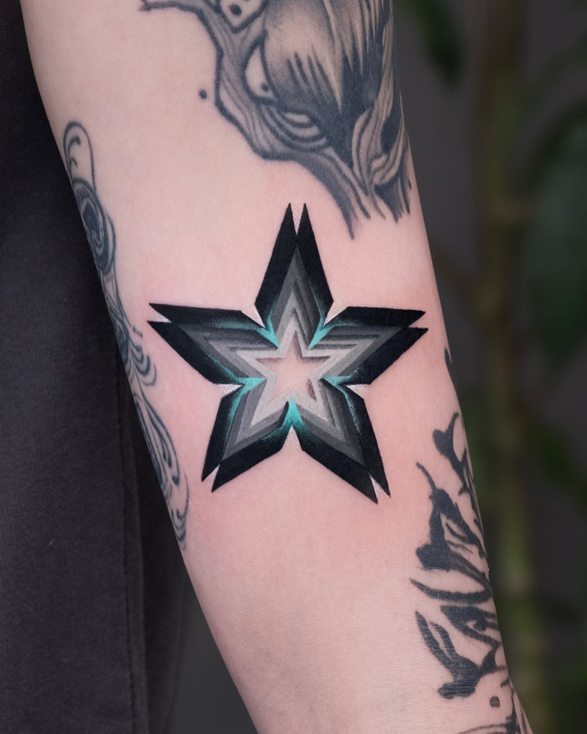 3D star tattoo with alternating facets and grey shading on a person's arm