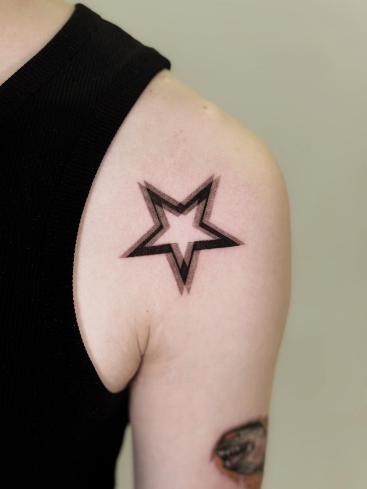 Five-pointed star tattoo with bold black outlines on a person's upper arm.