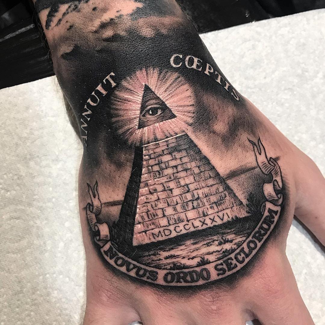 Eye of Providence pyramid tattoo on a hand with Latin text banners