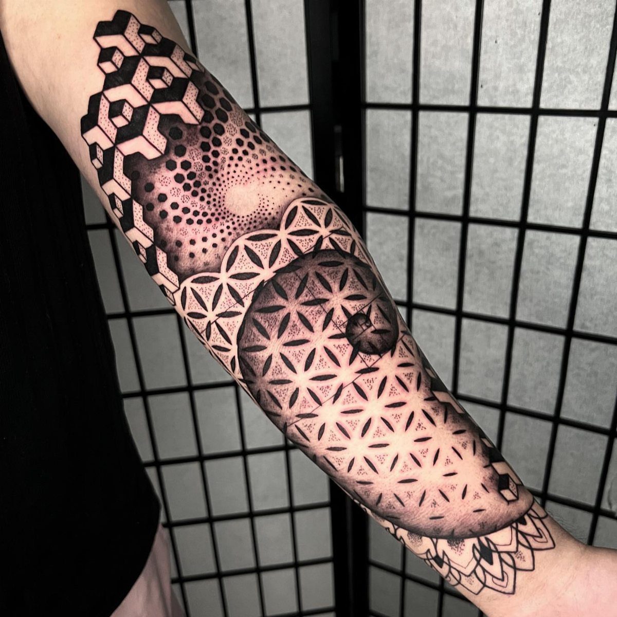 Geometric forearm tattoo featuring a large circular mandala and 3D isometric cubes.