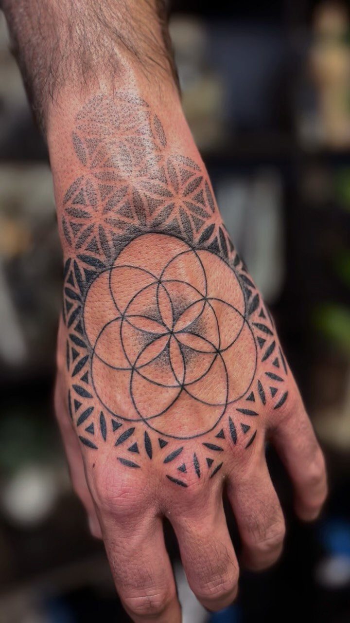 Flower of Life sacred geometry tattoo on the back of a person's hand.