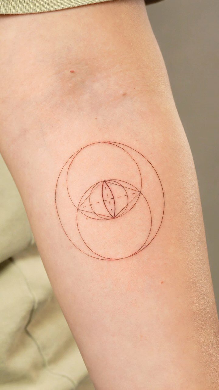 Vesica Piscis tattoo on a forearm with red ink and geometric details
