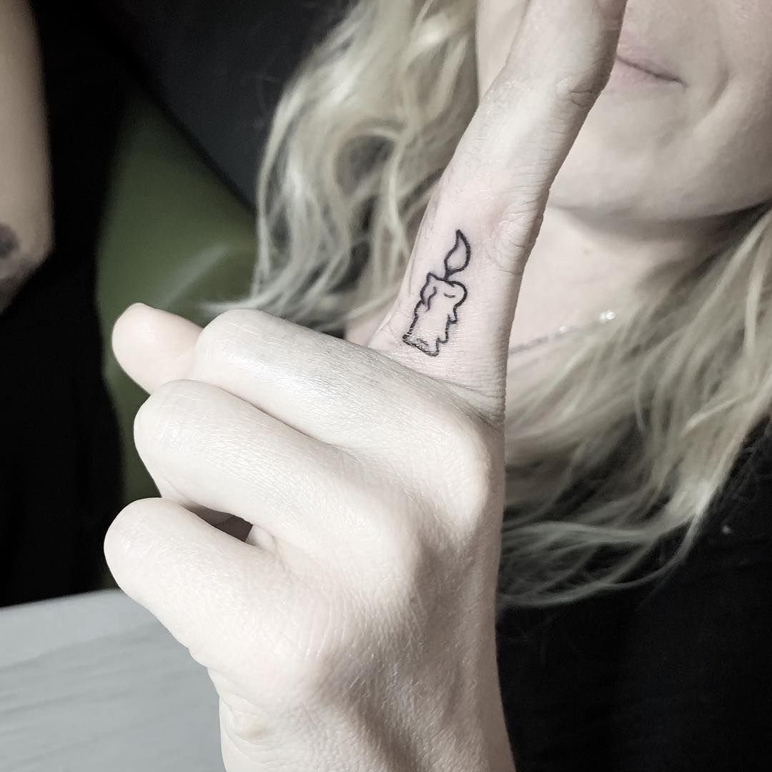 Small black ink candle tattoo on the side of a person's index finger