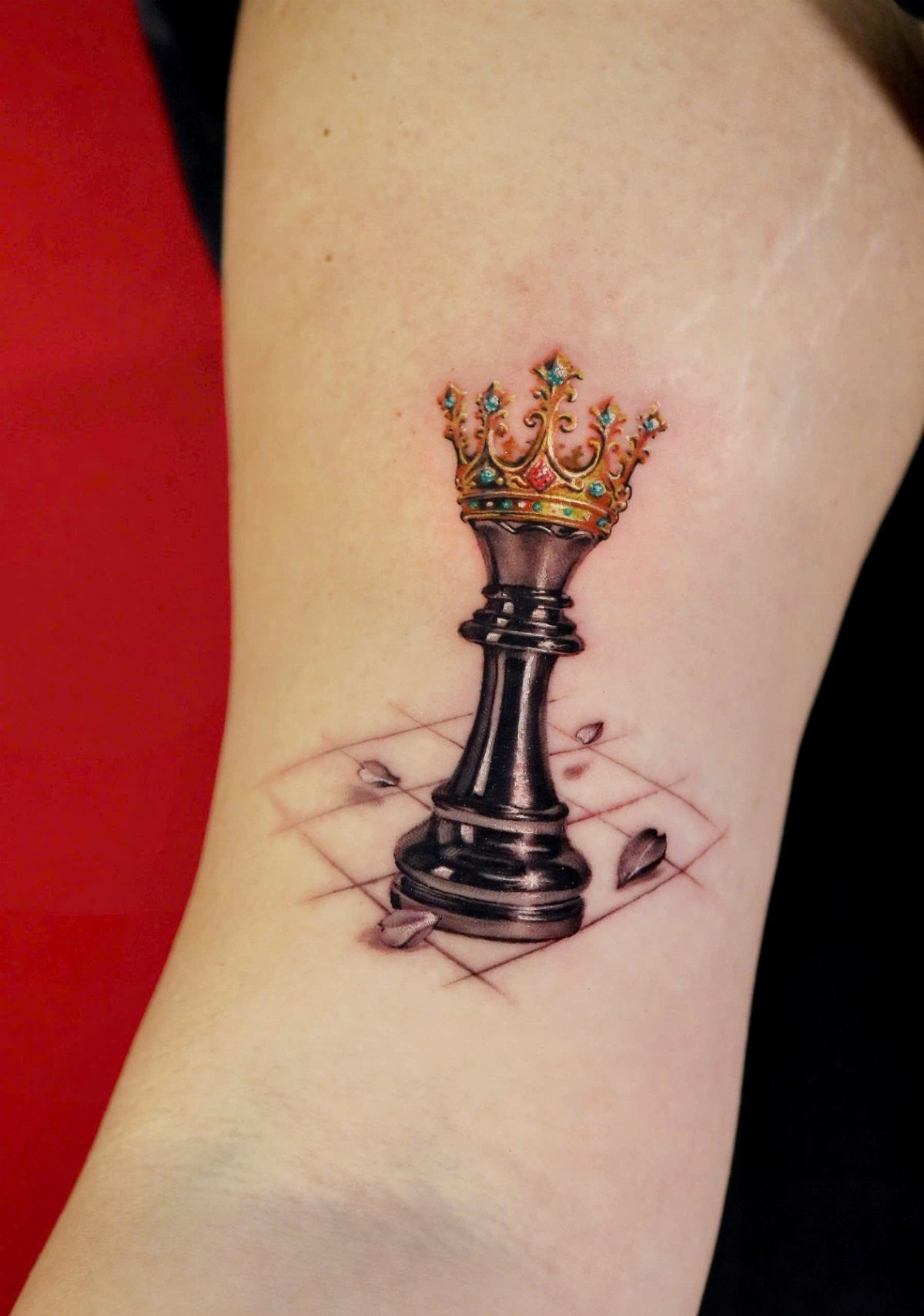 Black chess queen tattoo with a gold crown on a perspective chessboard grid.
