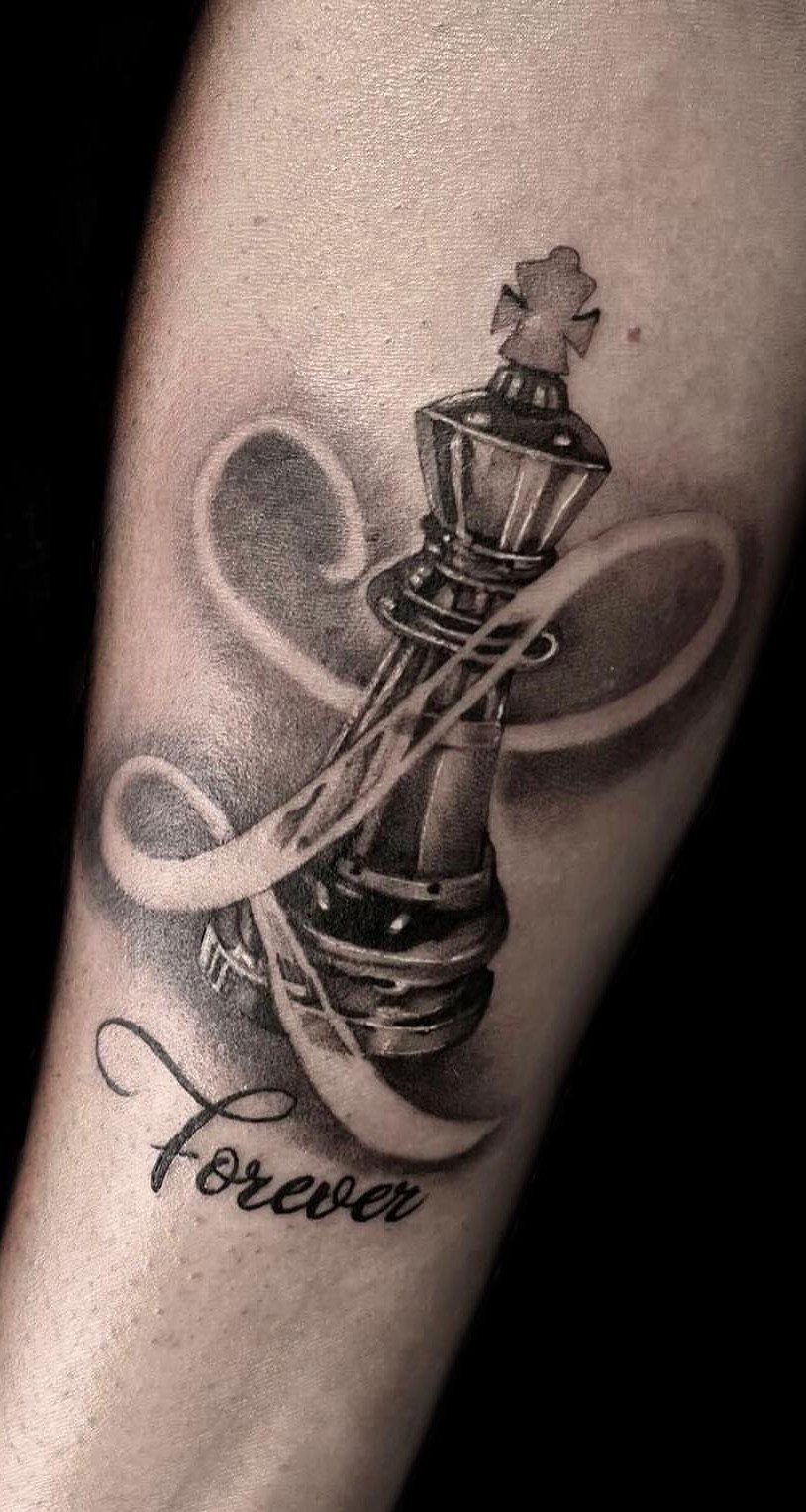 Queen chess piece tattoo with a flowing ribbon and the word Forever.