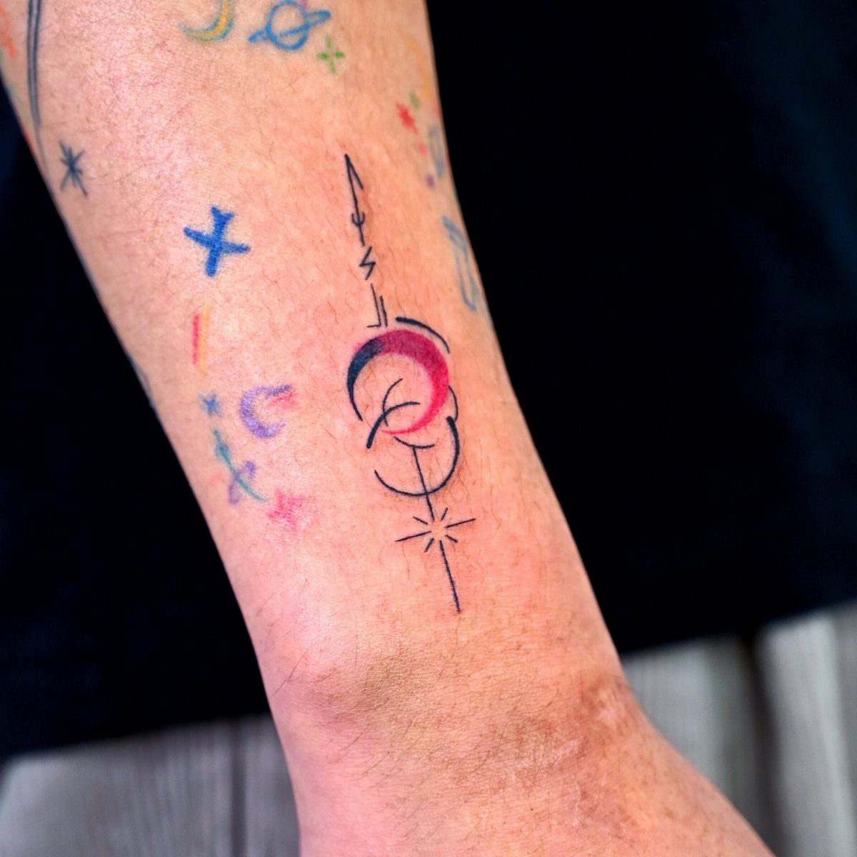 Crescent moon tattoo with geometric lines and a star on a forearm