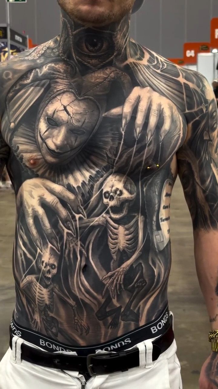 Tattooed torso featuring a creepy clown and skeletons in black and grey ink.
