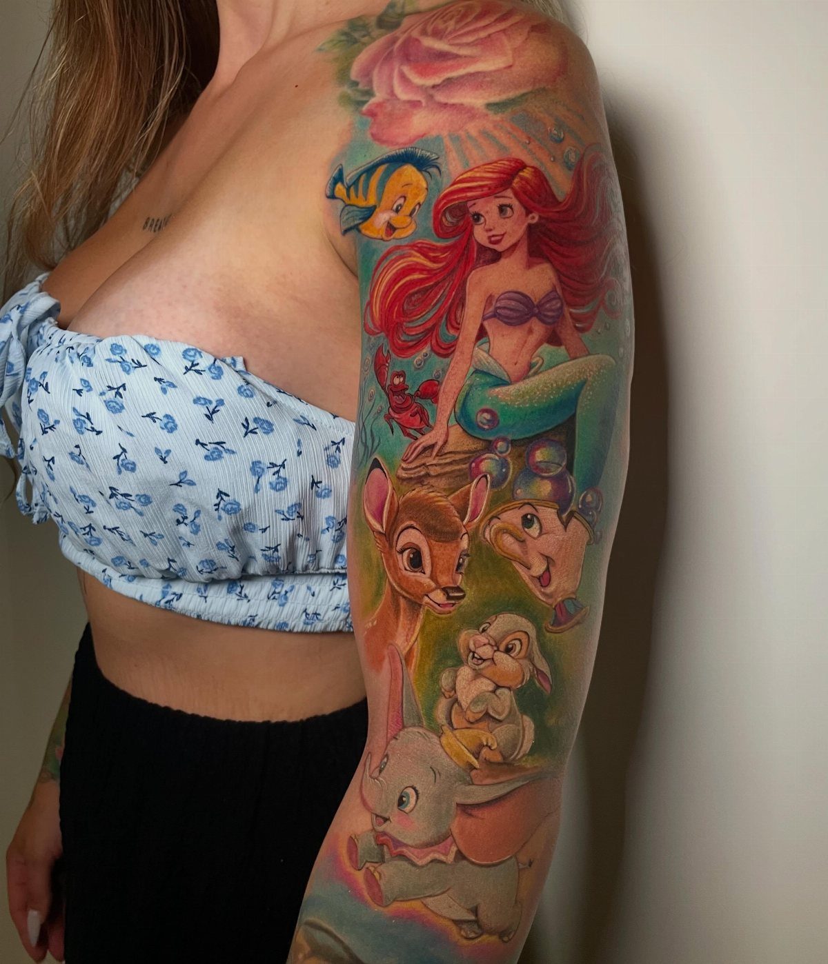 Colorful Disney character sleeve tattoo featuring Ariel, Bambi, and other classic animated figures.