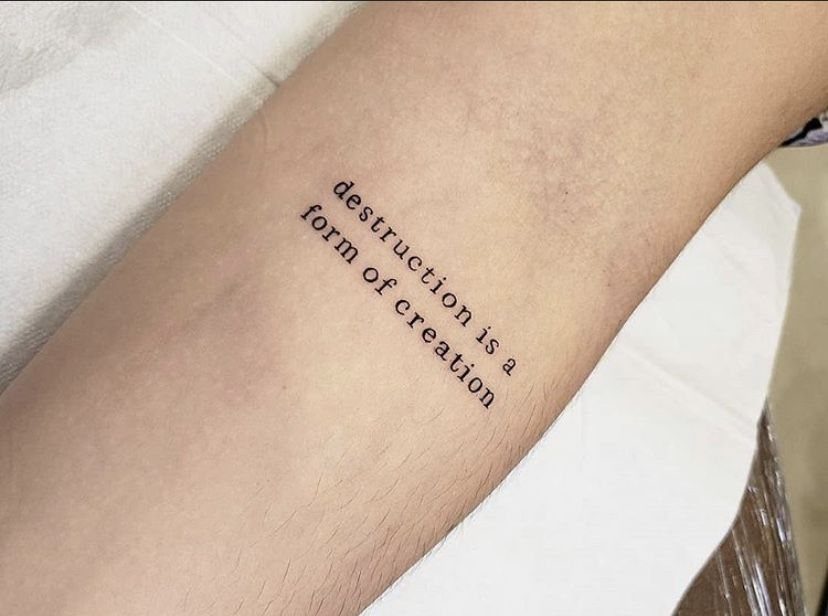 Tattoo on a forearm reading destruction is a form of creation in black ink