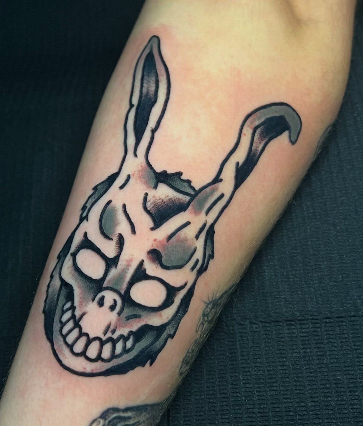 Skeletal rabbit Frank tattoo with bold outlines on a person's forearm.