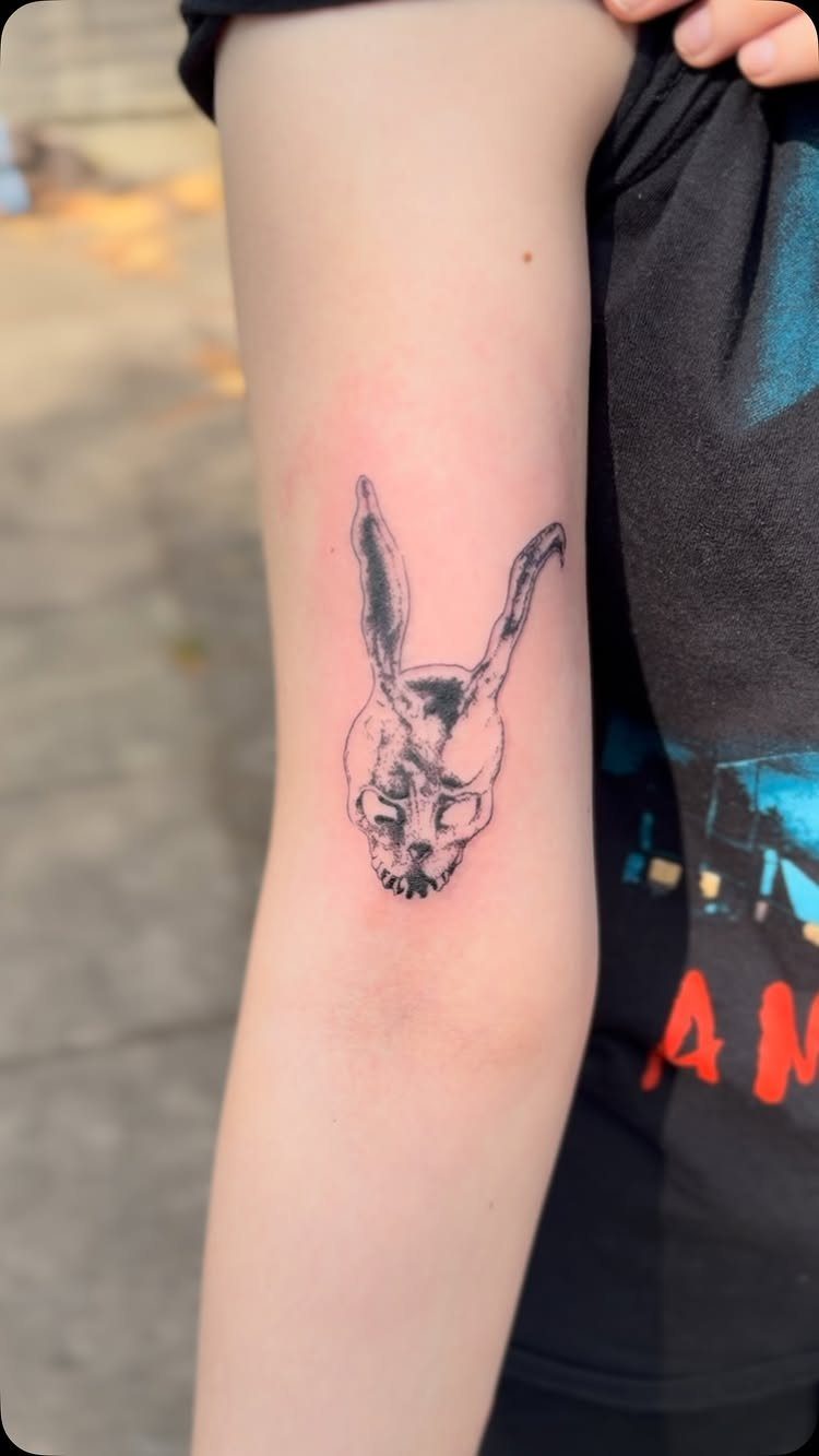 Skeletal rabbit head tattoo on a person's upper arm with black ink.
