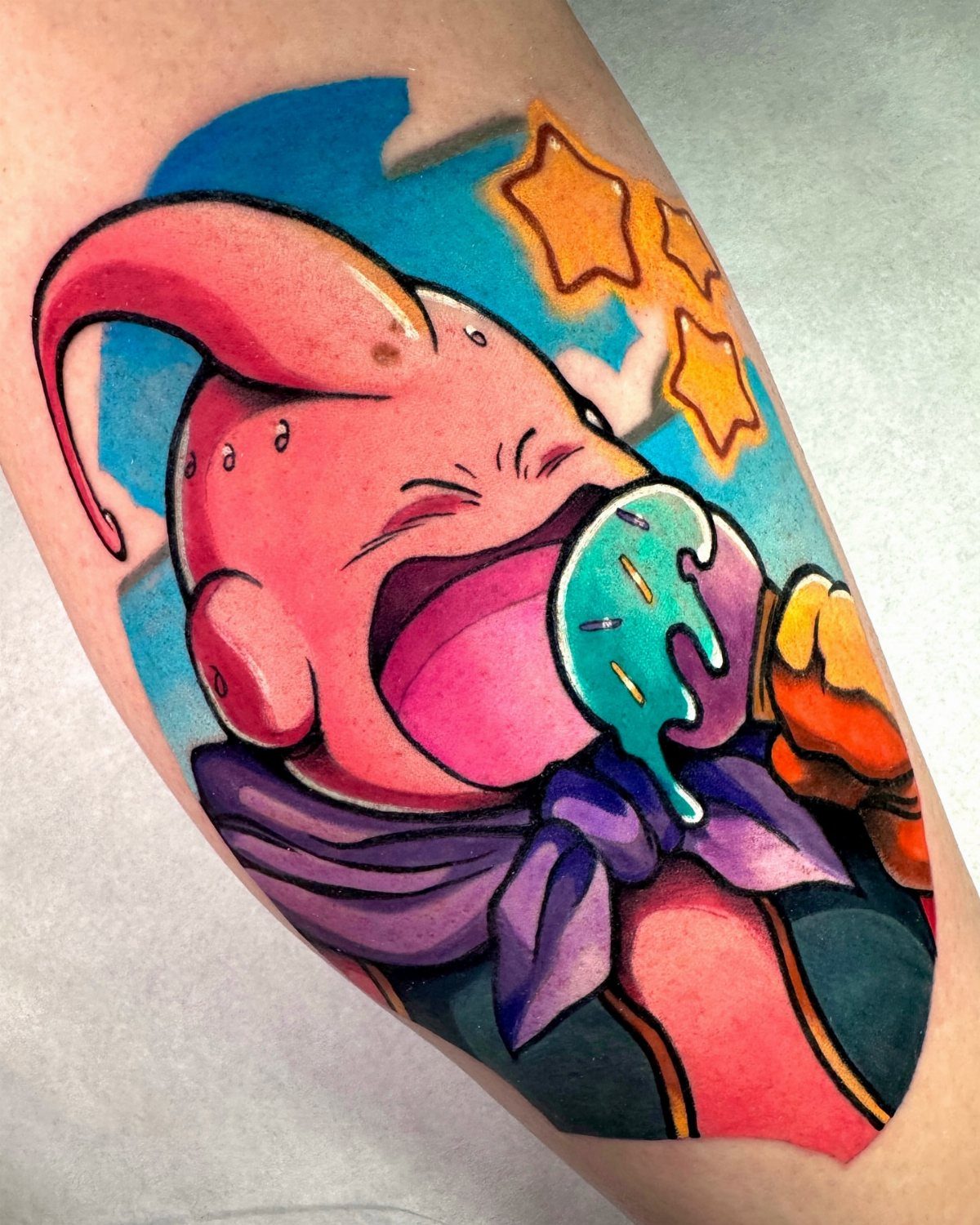 Majin Buu tattoo eating a blue popsicle with yellow stars on a blue background