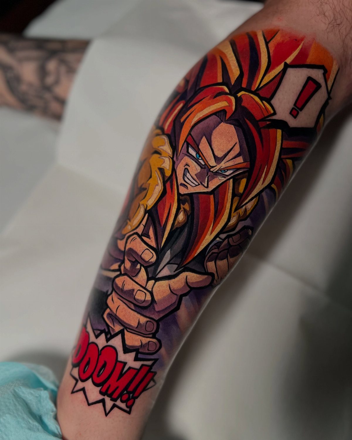 Super Saiyan 4 Goku tattoo on an arm with comic-style action text