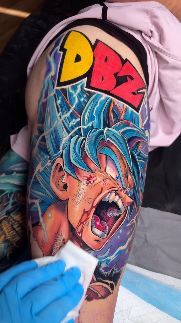 Goku tattoo with blue hair and DBZ text on a person's thigh