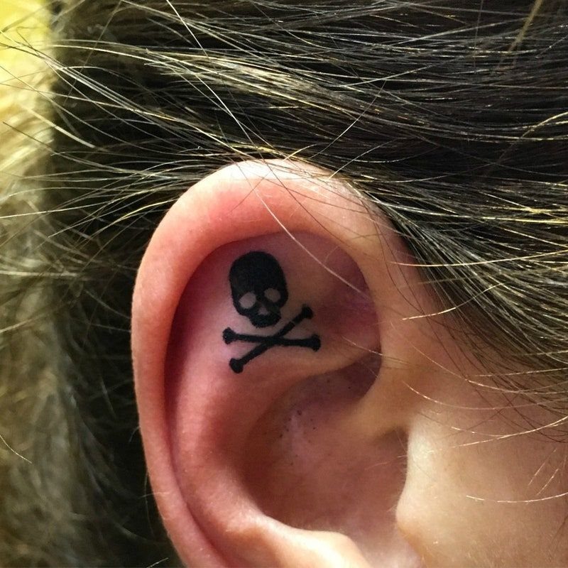 Skull and crossbones tattoo on the inner part of a human ear.