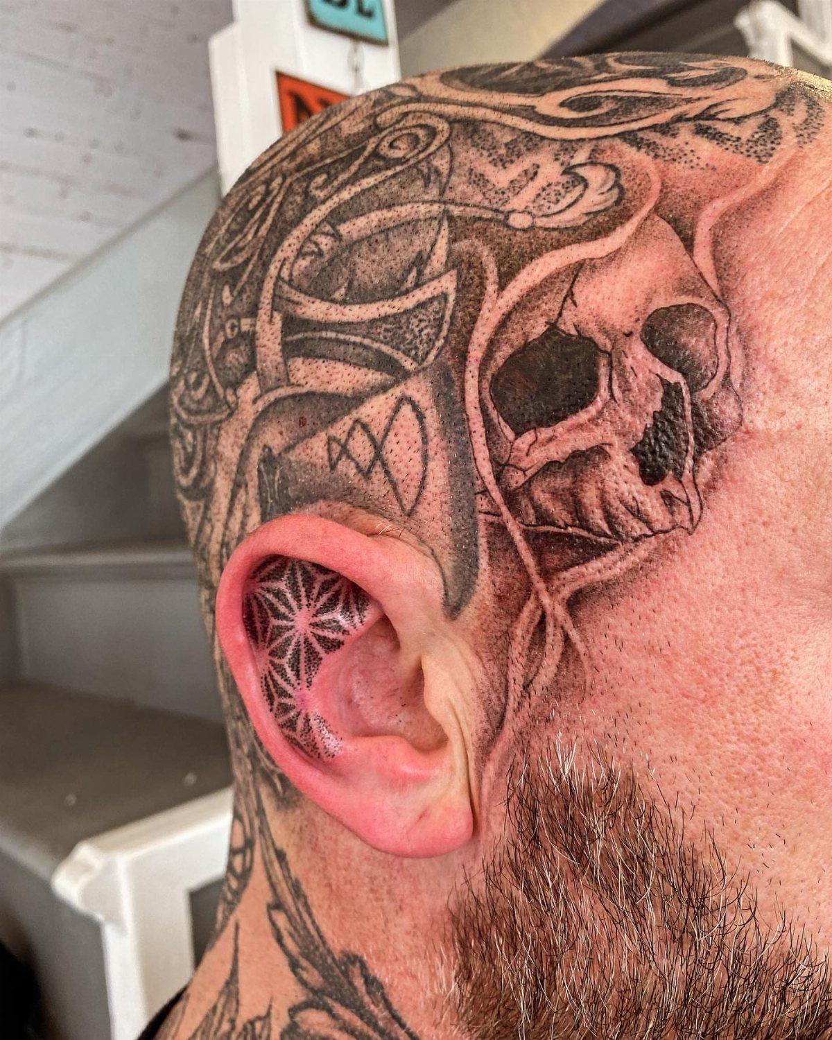 Skull tattoo on a man's head with a geometric pattern inside the ear.