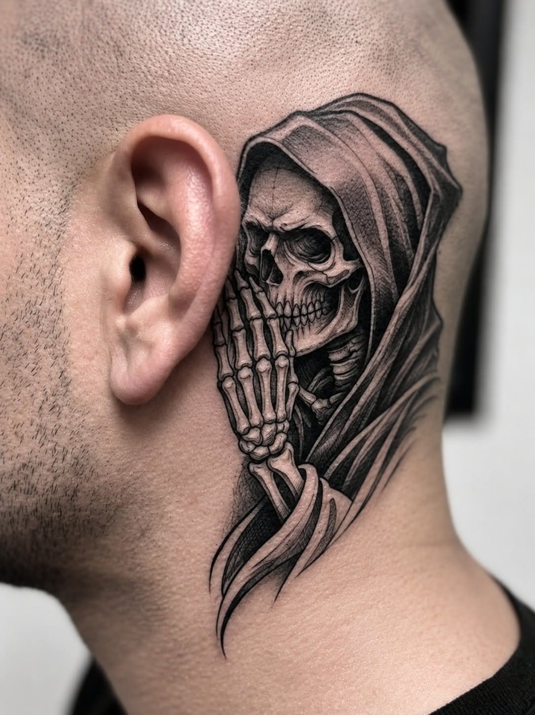 Skull wearing a hood tattoo with a skeletal hand on a man's neck.