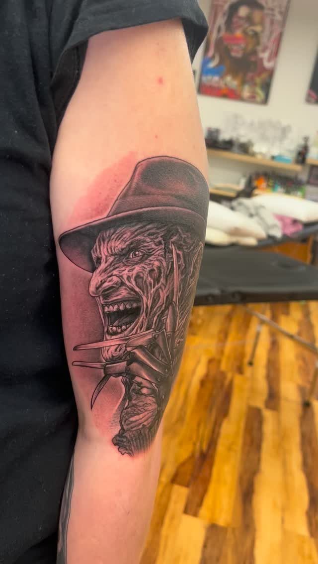 Freddy Krueger portrait tattoo on an arm featuring his scarred face and clawed glove.