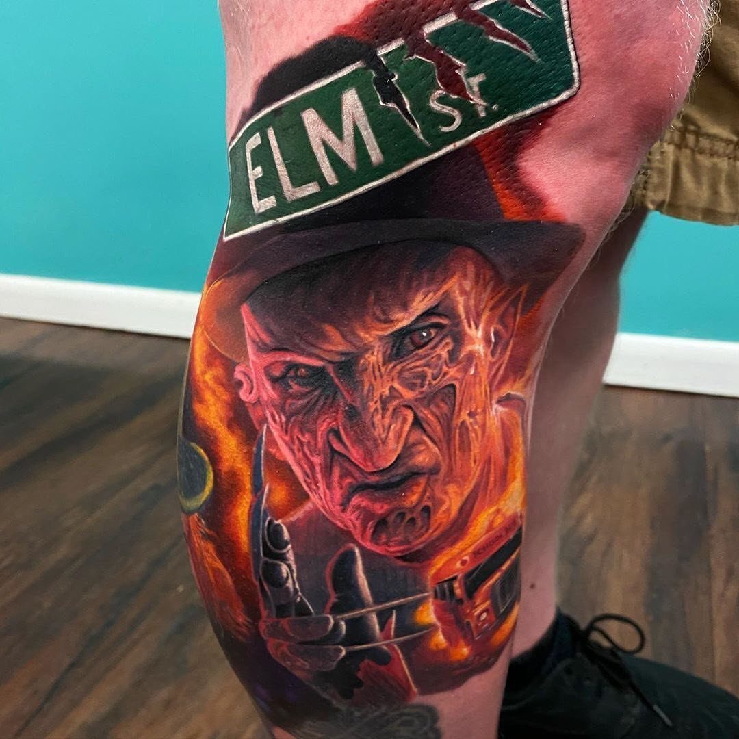 Freddy Krueger tattoo on a leg featuring his face and an Elm Street sign.