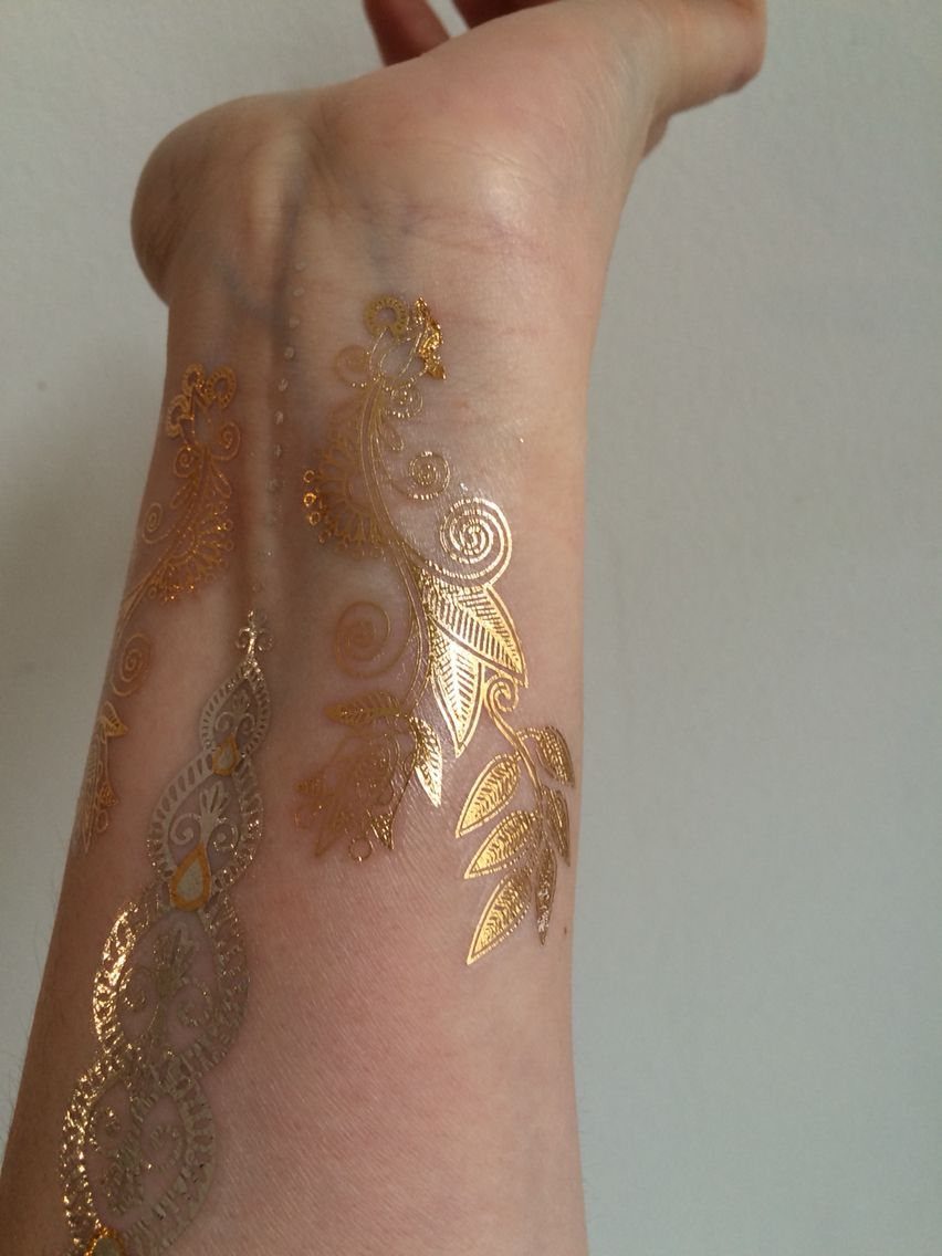 Gold metallic ink floral and paisley patterns on a person's forearm and wrist.