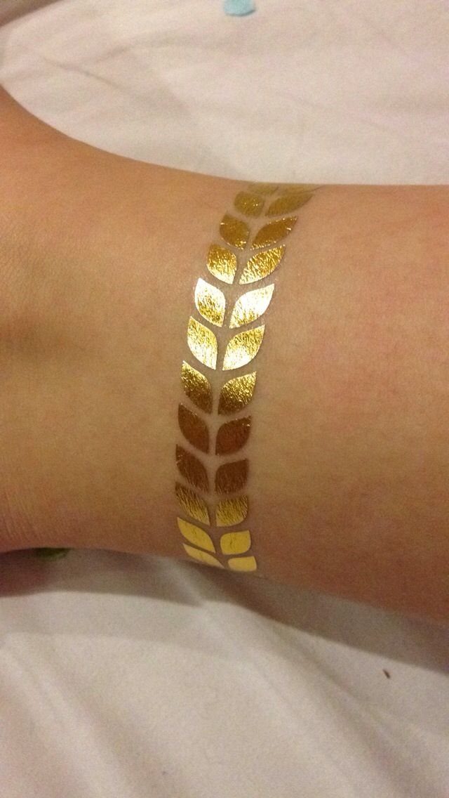 Gold metallic laurel leaf temporary tattoo applied to a person's wrist.