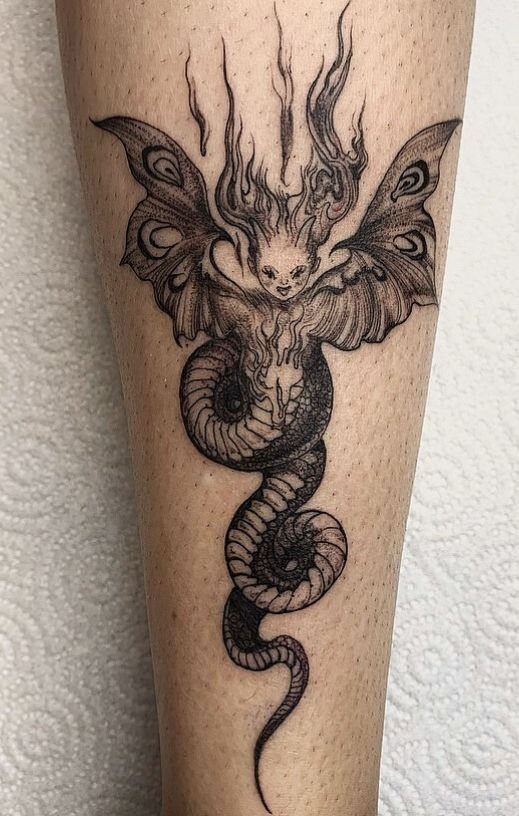 Dark fairy tattoo with bat wings entwined with a coiled snake on skin