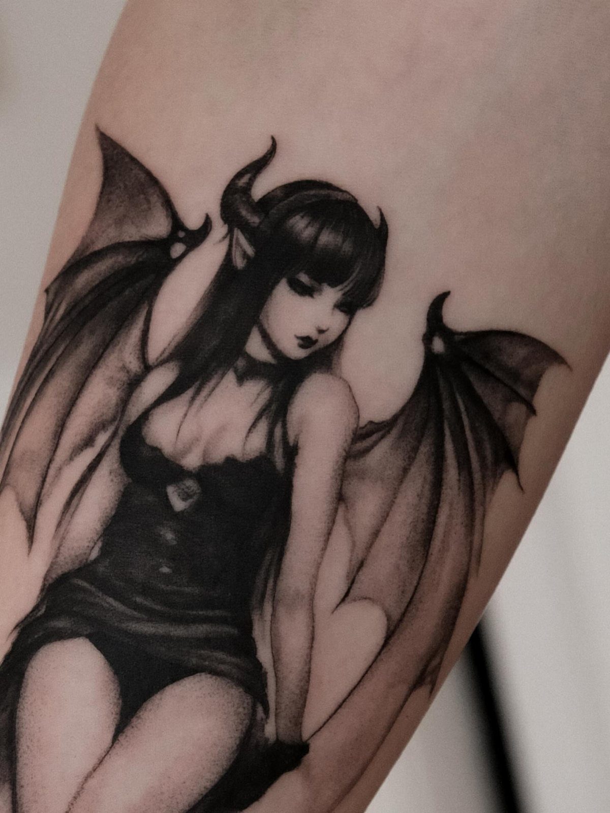 Gothic fairy tattoo with bat wings and horns on a person's arm.