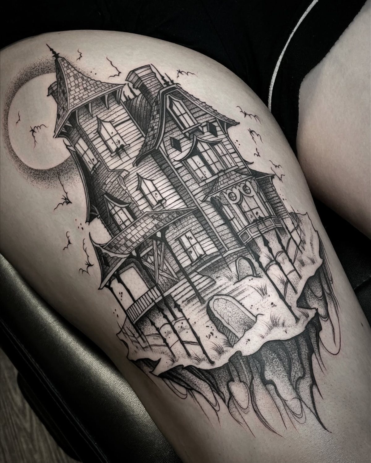 Detailed fine line tattoo of a spooky haunted house on a cliff with moon.