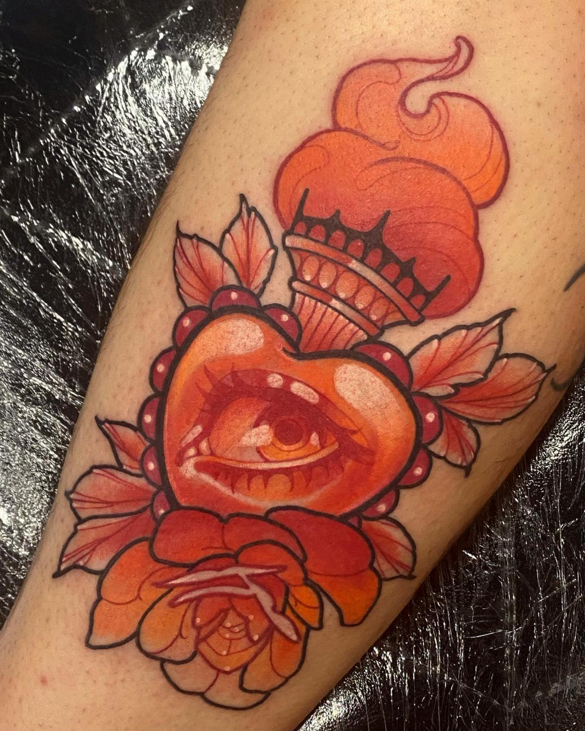 Red heart tattoo with a central eye, orange flames, and a rose.