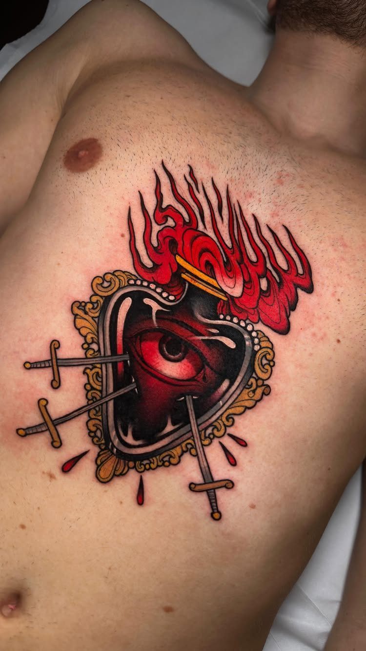 Sacred heart tattoo with a central eye, red flames, and three piercing swords.