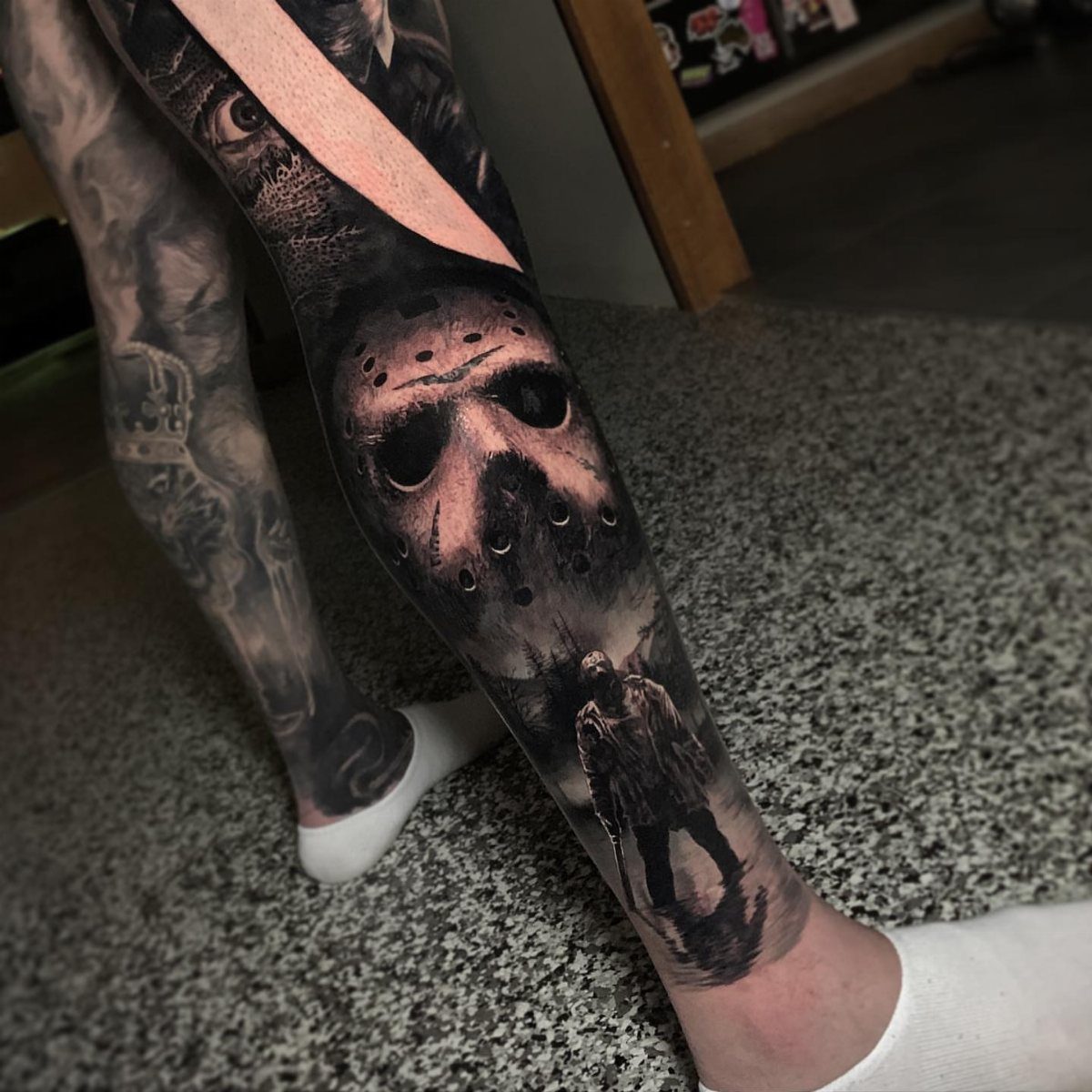 Jason Voorhees hockey mask and figure with machete tattooed on a person's leg