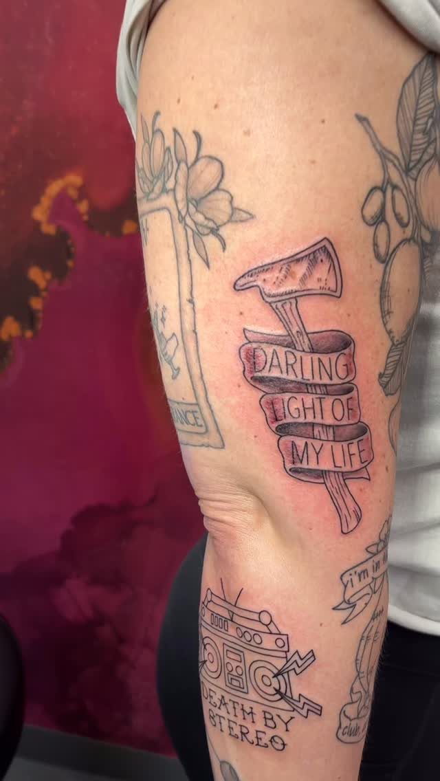 Blood-stained axe tattoo with a banner reading Darling Light of My Life on arm