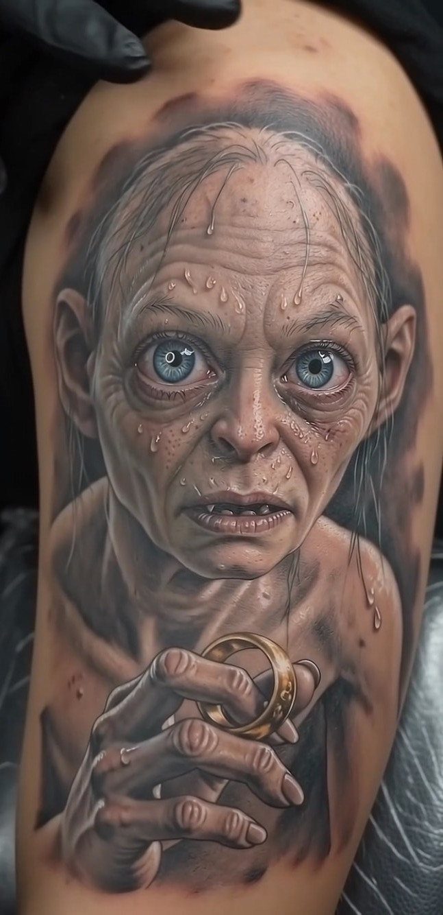 Hyper-realistic tattoo of Gollum holding a gold ring on a person's arm.