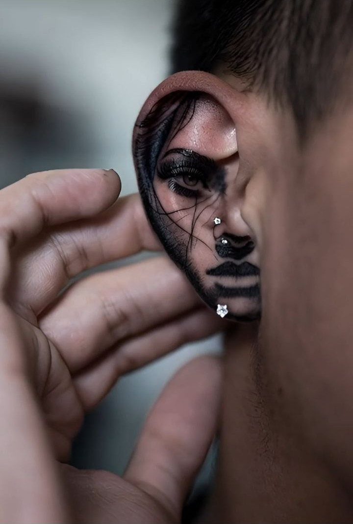 Hyper-realistic portrait tattoo of a woman's face on a person's outer ear.