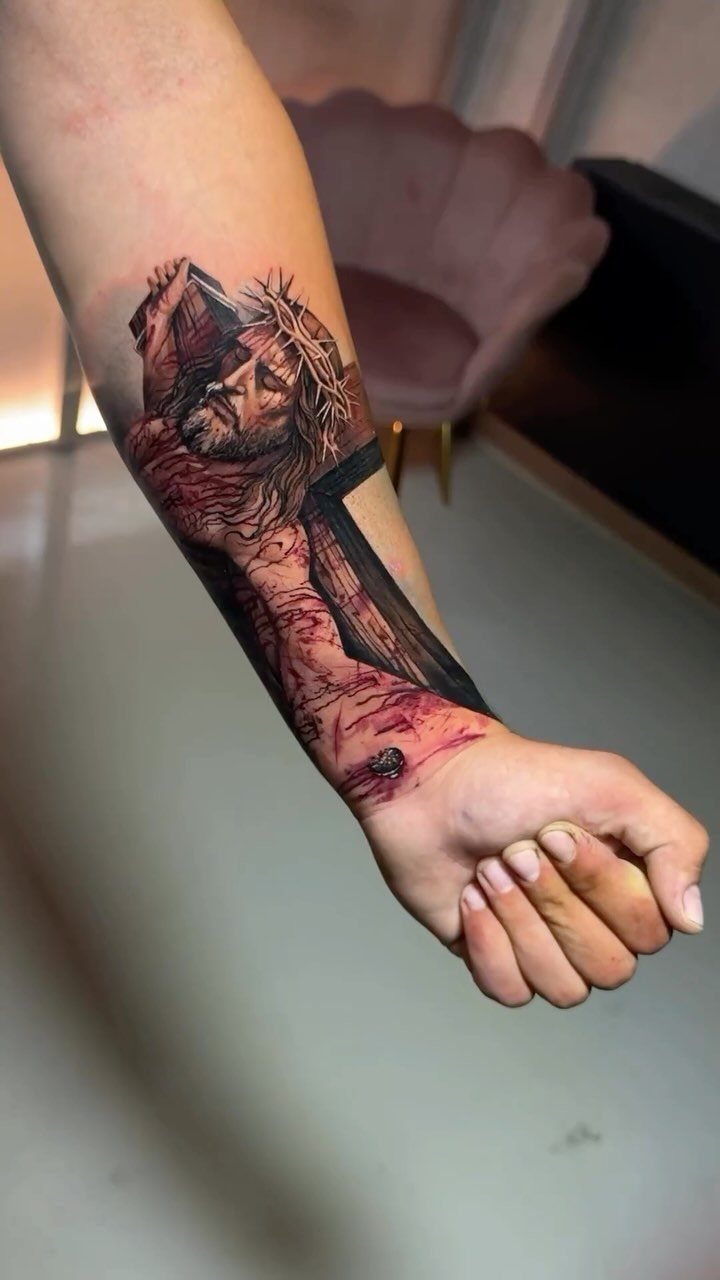 Hyper-realistic tattoo of Jesus Christ with crown of thorns on a forearm