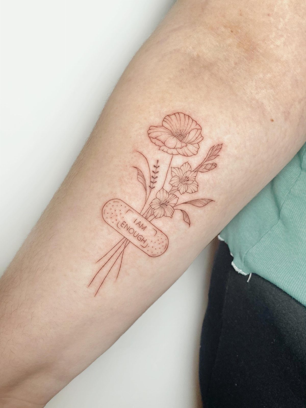 Red ink tattoo of flowers wrapped in a bandage saying I am enough