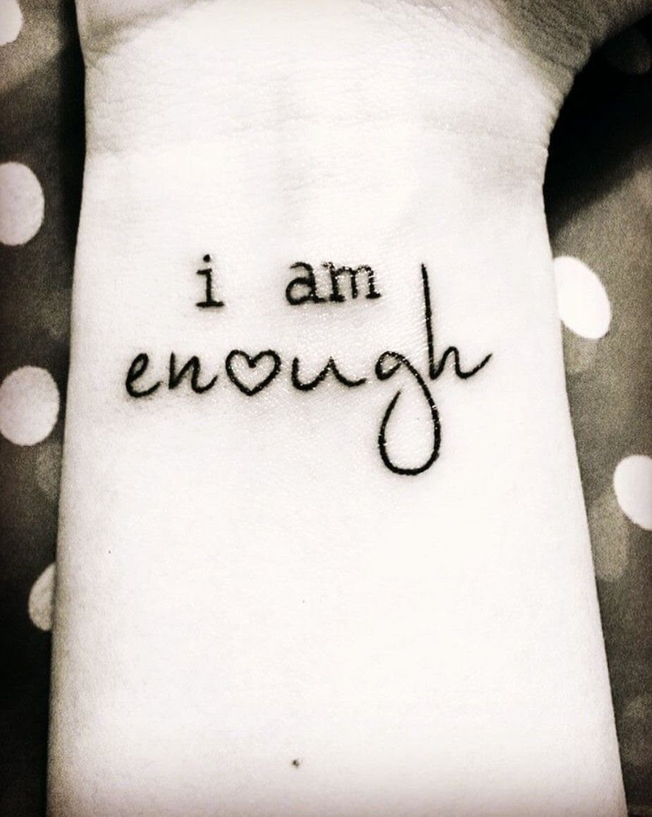 Wrist tattoo reading i am enough with a heart replacing the letter o
