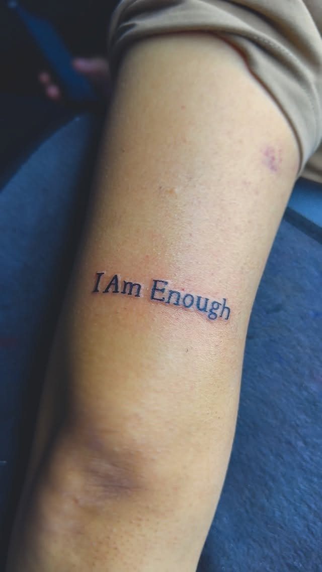 Forearm tattoo with the words I Am Enough in black serif font