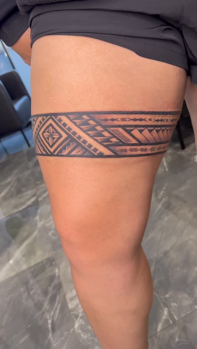 Geometric tribal band tattoo wrapped around a person's upper thigh.