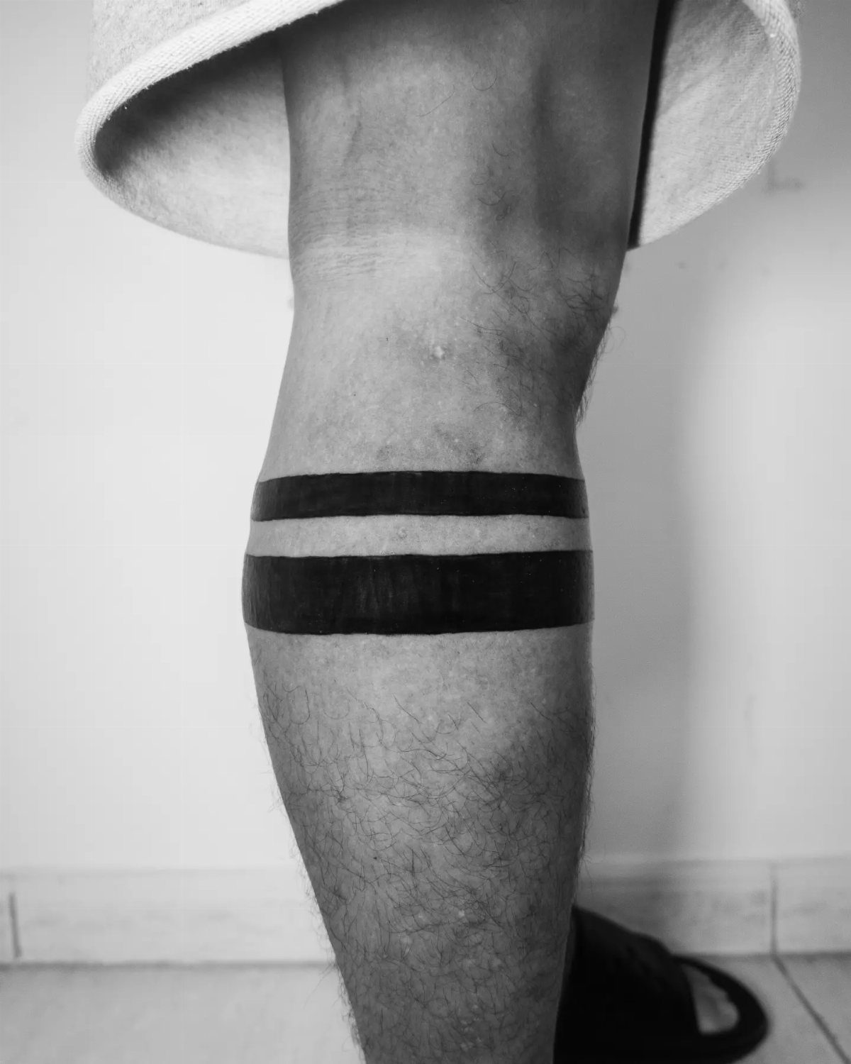 Lower leg with two thick solid black ink band tattoos wrapped around calf
