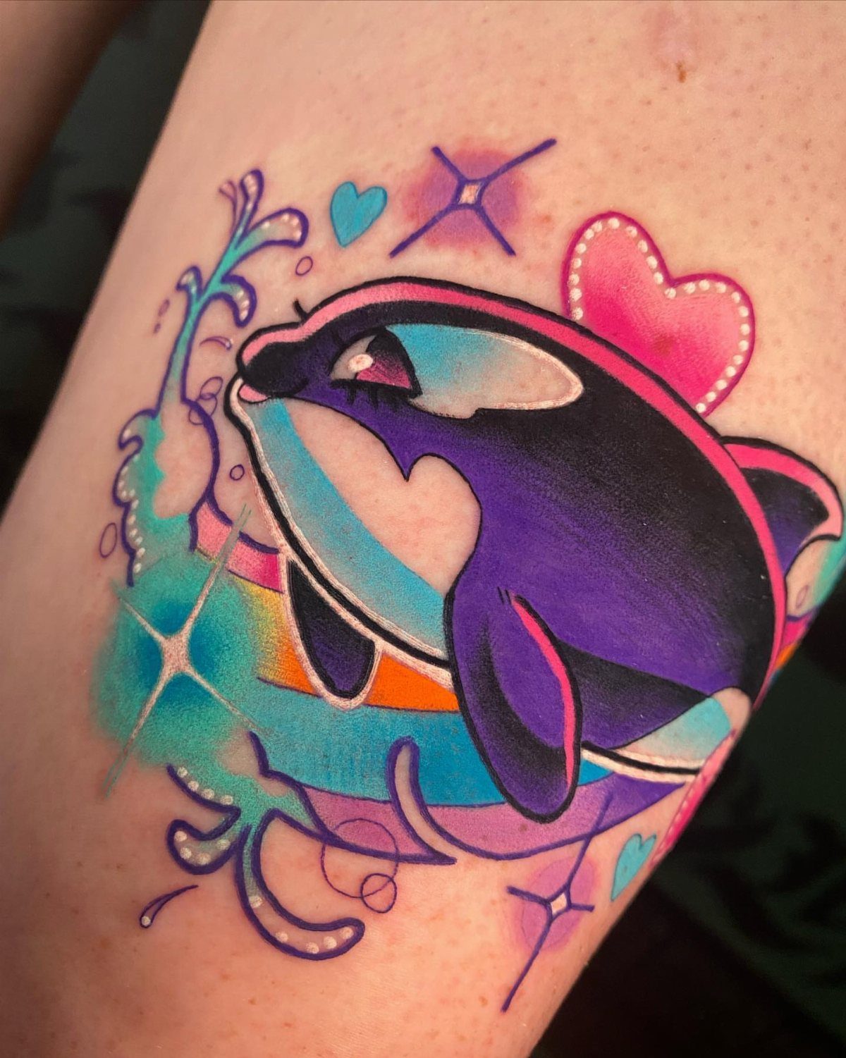 Colorful Lisa Frank style dolphin tattoo with a pink heart and blue water splashes.