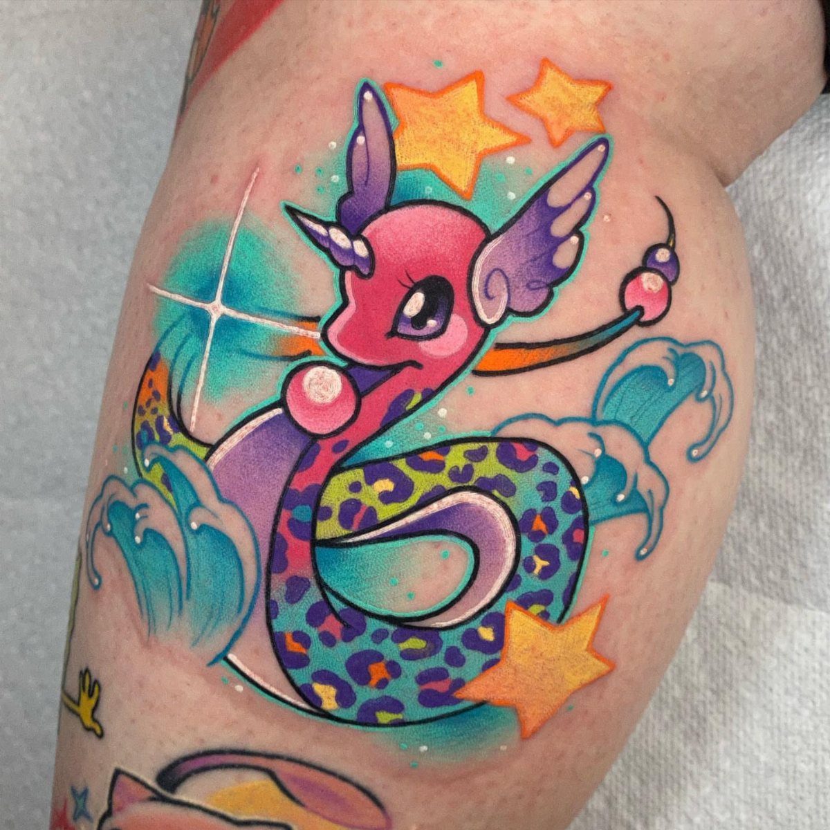 Colorful dragon tattoo with leopard spots and stars on a person's arm.