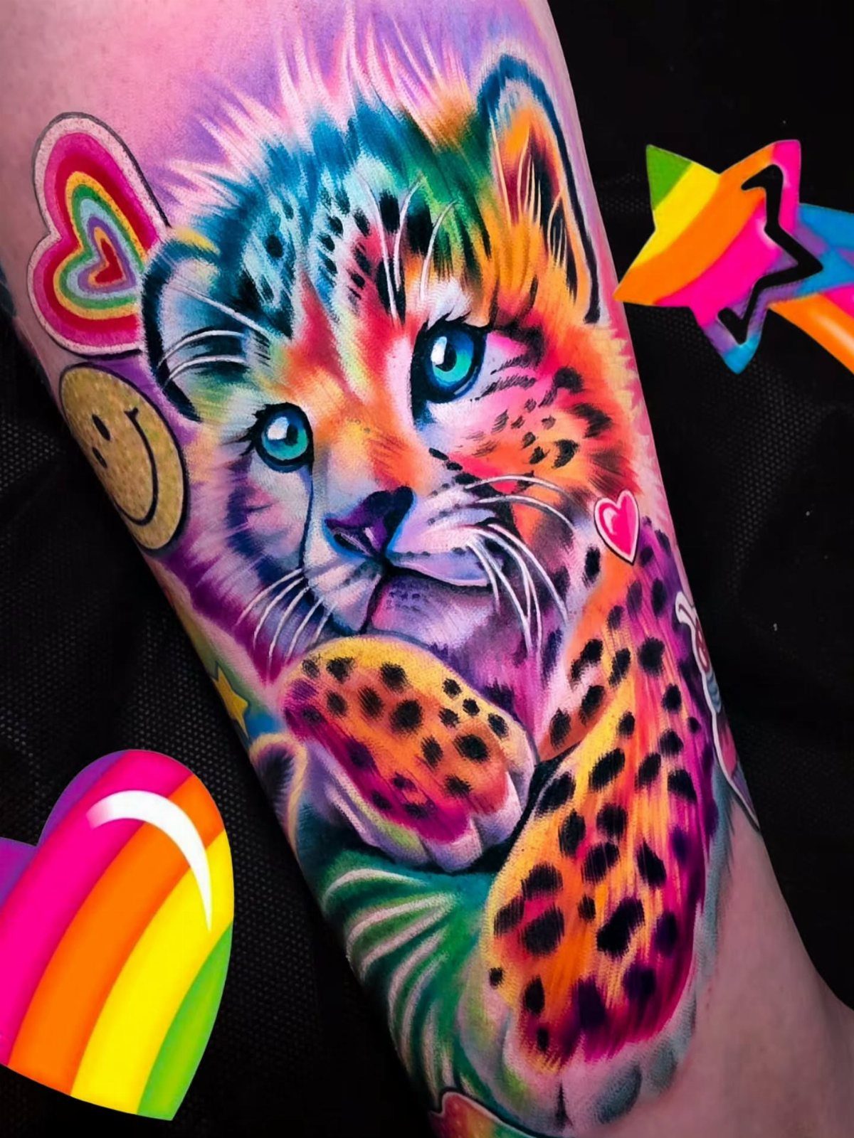 Colorful leopard cub tattoo with rainbow hearts and smiley face on an arm