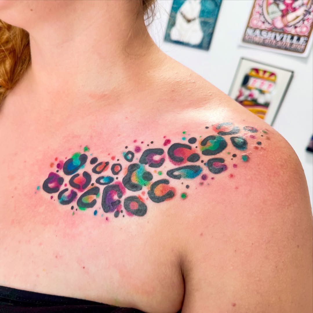 Rainbow leopard spot tattoo on a person's shoulder and collarbone area.