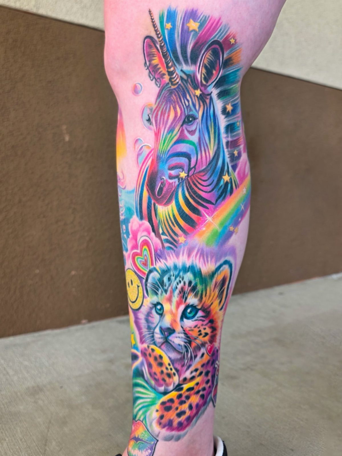 Rainbow zebra and leopard tattoos on a leg in vibrant neon colors.