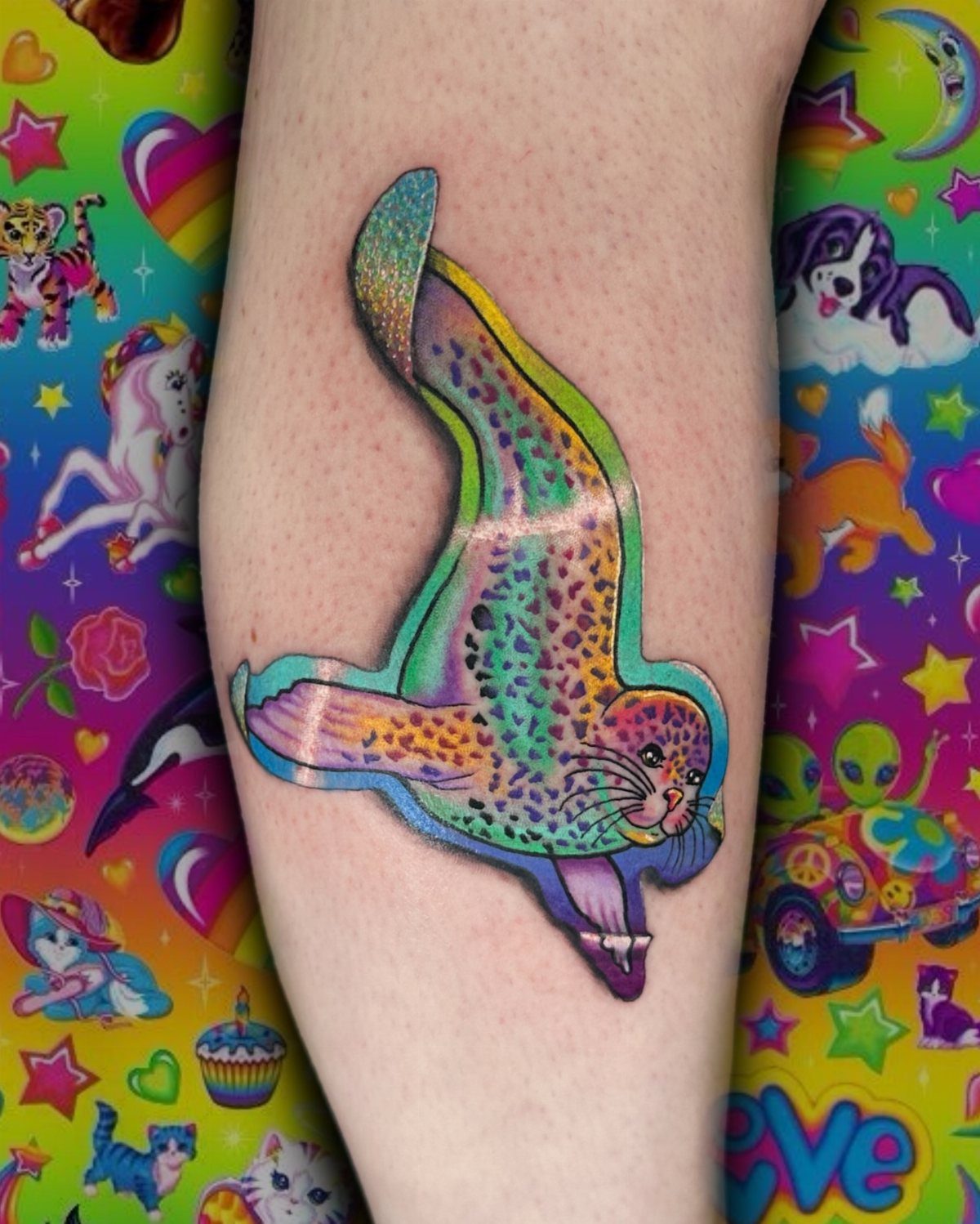 Rainbow seal tattoo with leopard spots on a person's arm.