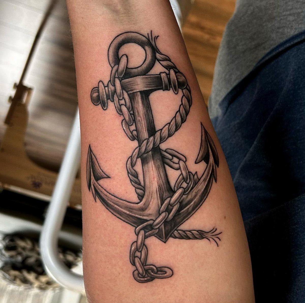 Anchor tattoo with rope and chain on a person's forearm.