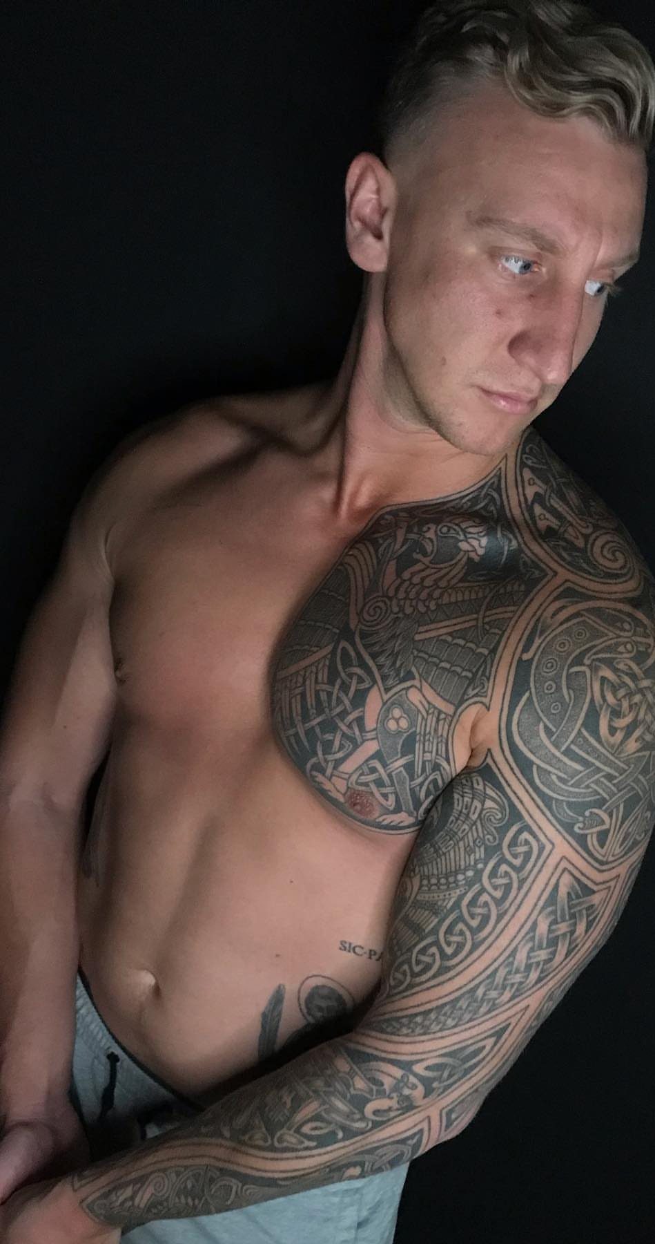 Muscular man with detailed Celtic knot tattoos covering his shoulder and arm.