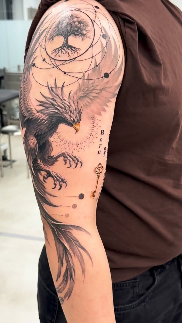 Phoenix tattoo on a man's arm featuring a tree of life and a key.