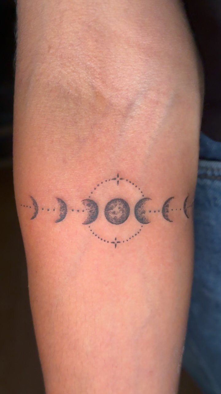 Moon phase tattoo on a forearm with a dotted circle around the full moon.